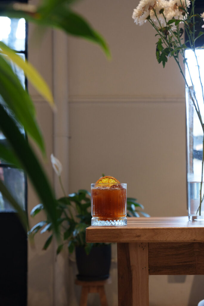 Espresso tonic con rodaja de naranja deshidratada sobre una mesa de madera en Gorrión