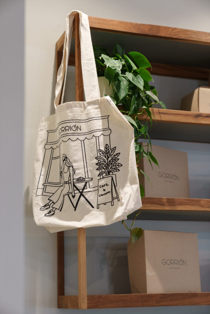 Tote bag Gorrión ilustrada con una chica tomando café en la vereda, ideal para regalar